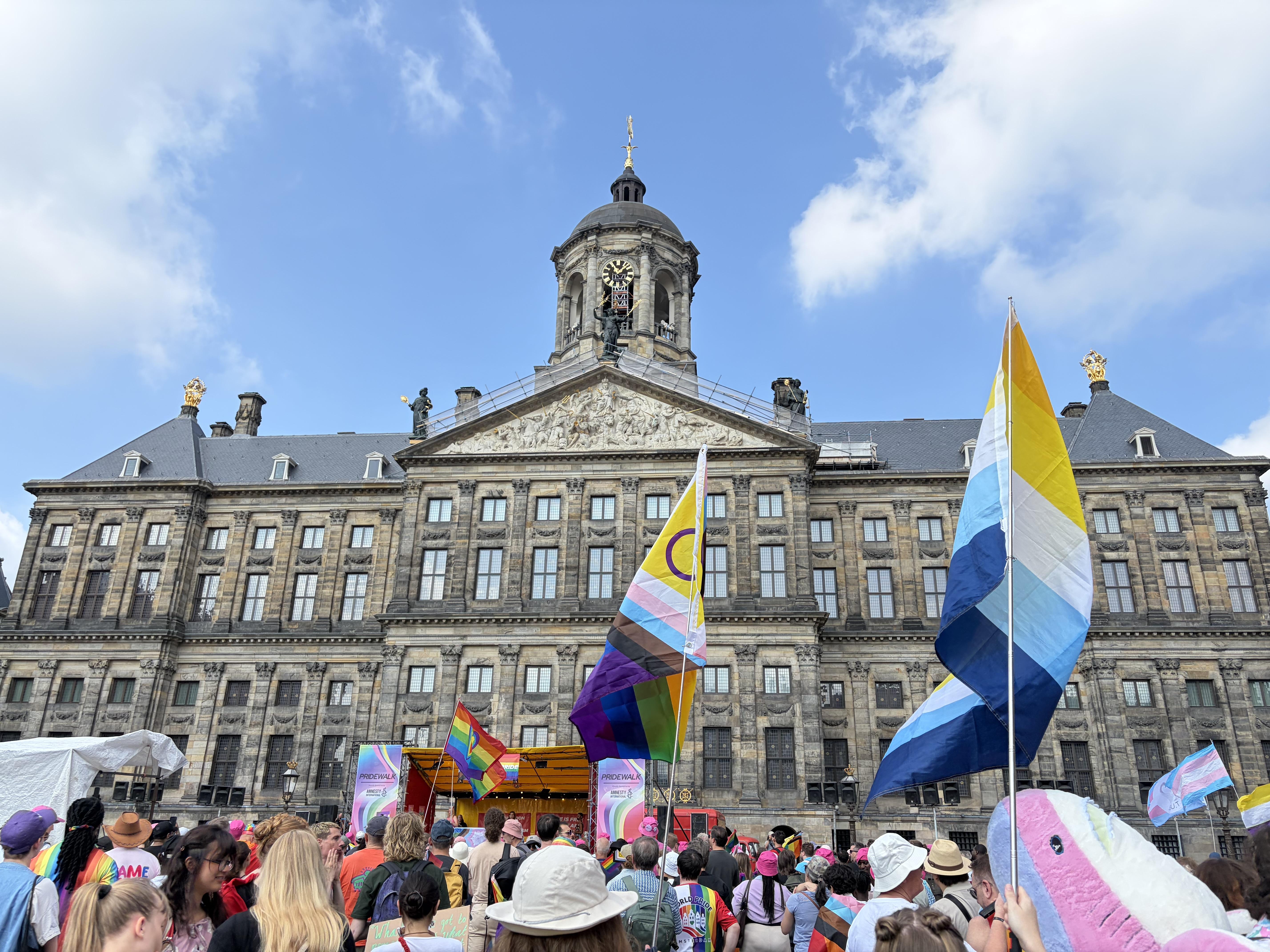 Royal Palace Amsterdam with many people waving pride flags