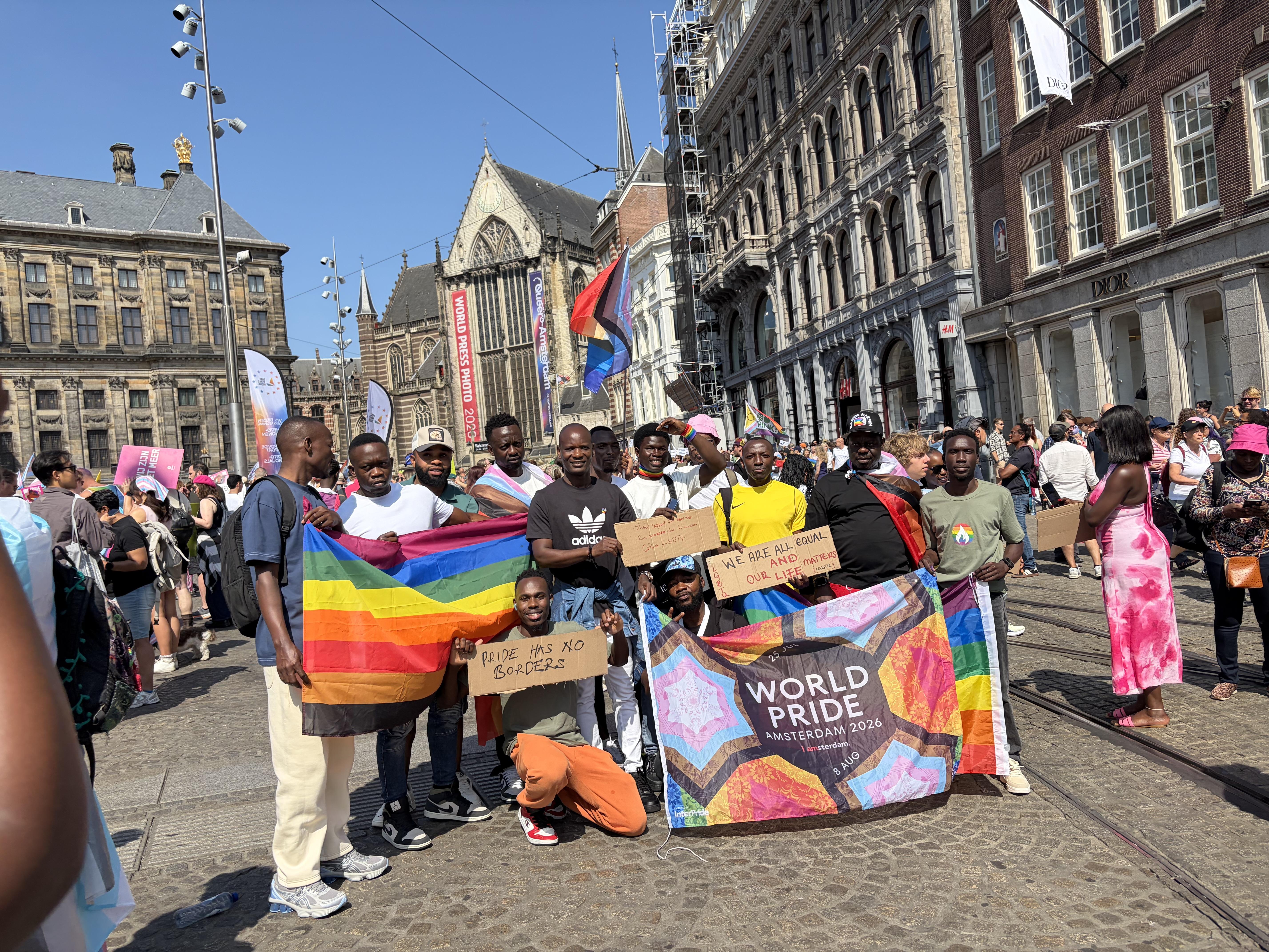 World Pride flag being held my many black folks in Dams Square Amsterdam