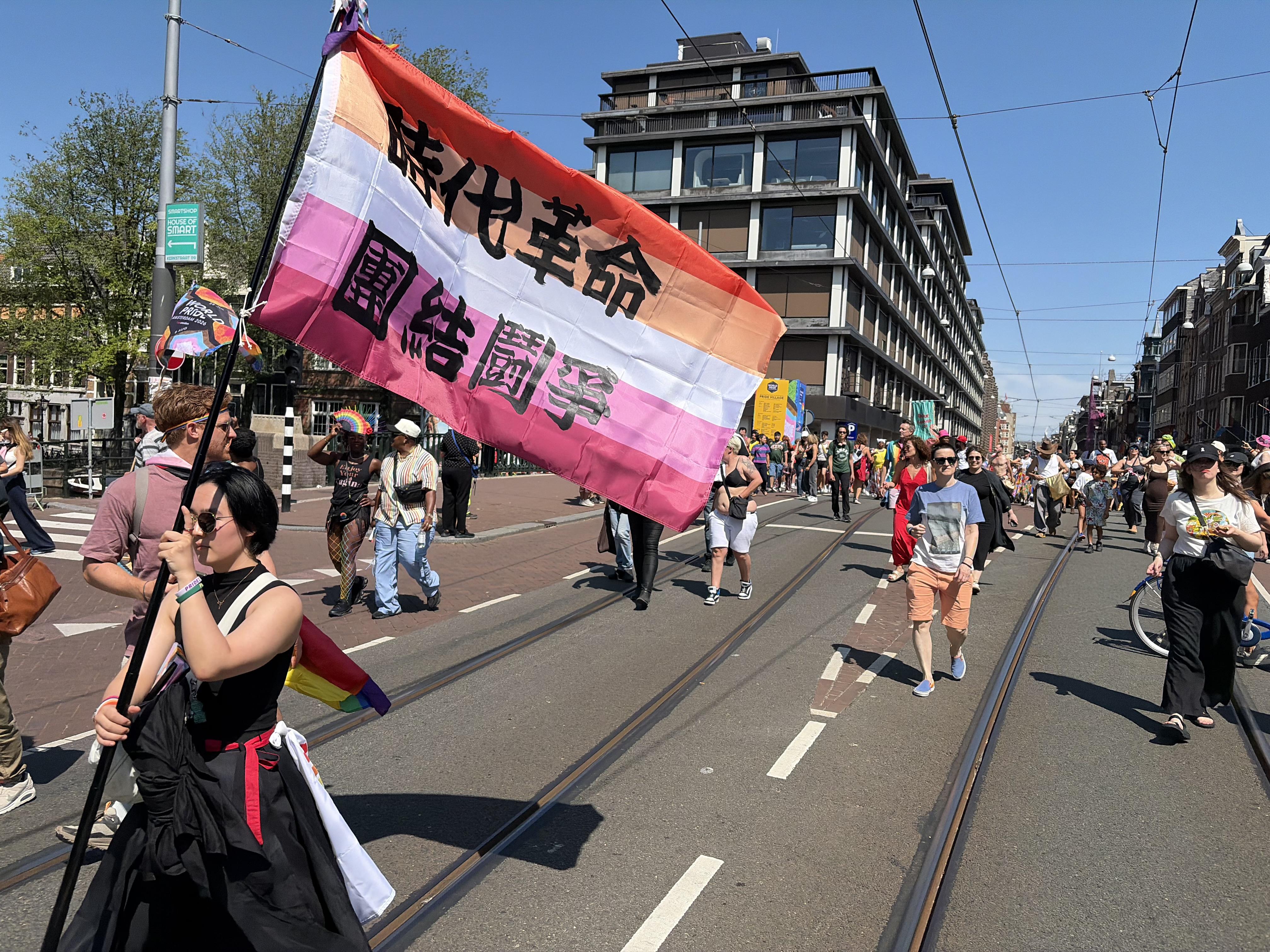 Pride Walk in Amsterdam, person holding a pride flag