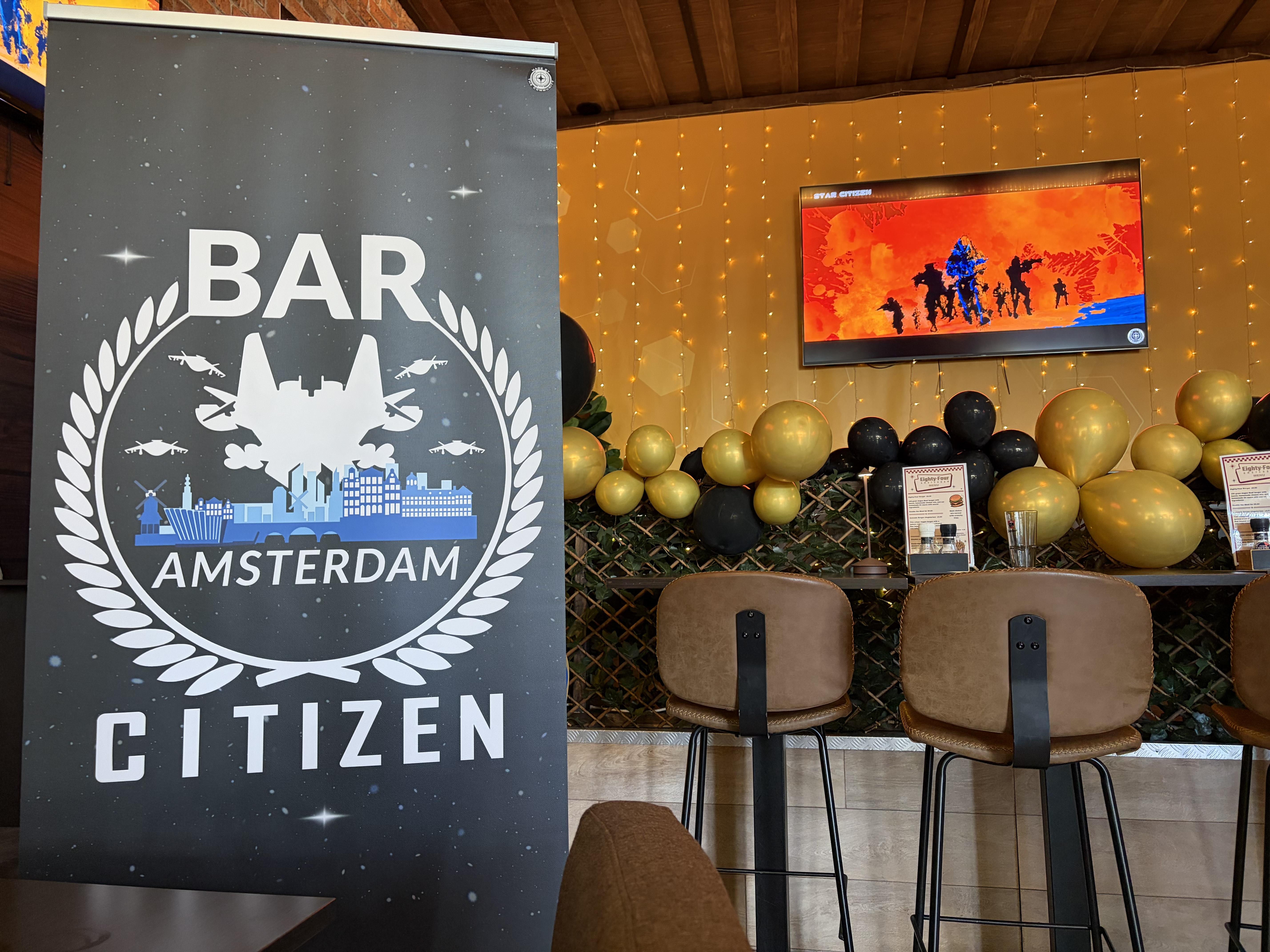 a Bar Citizen Amsterdam banner with a TV in the background playing Star Citizen B role