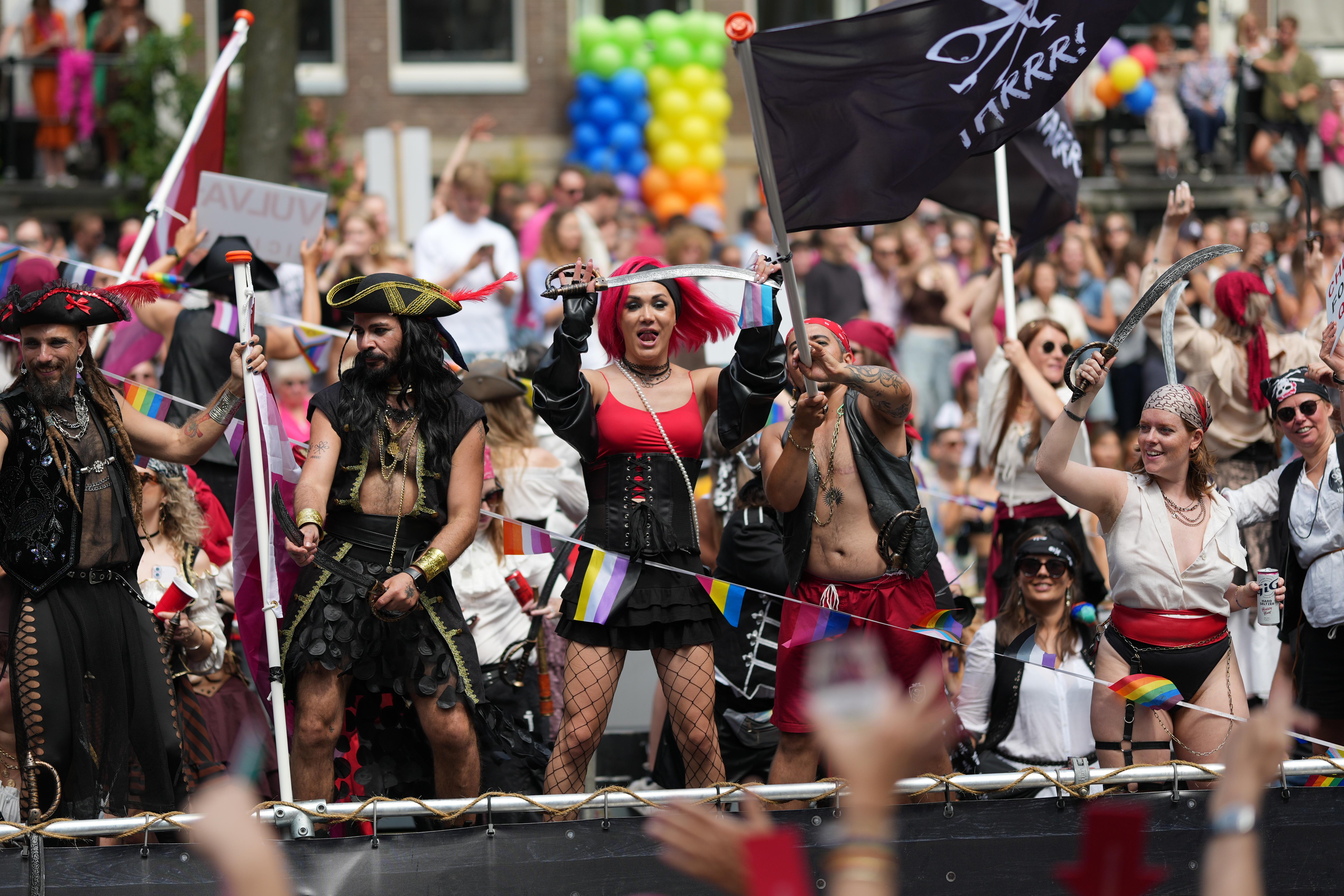 many pirates waving apparently metal swords on a boat at Canal Pride in Amsterdam
