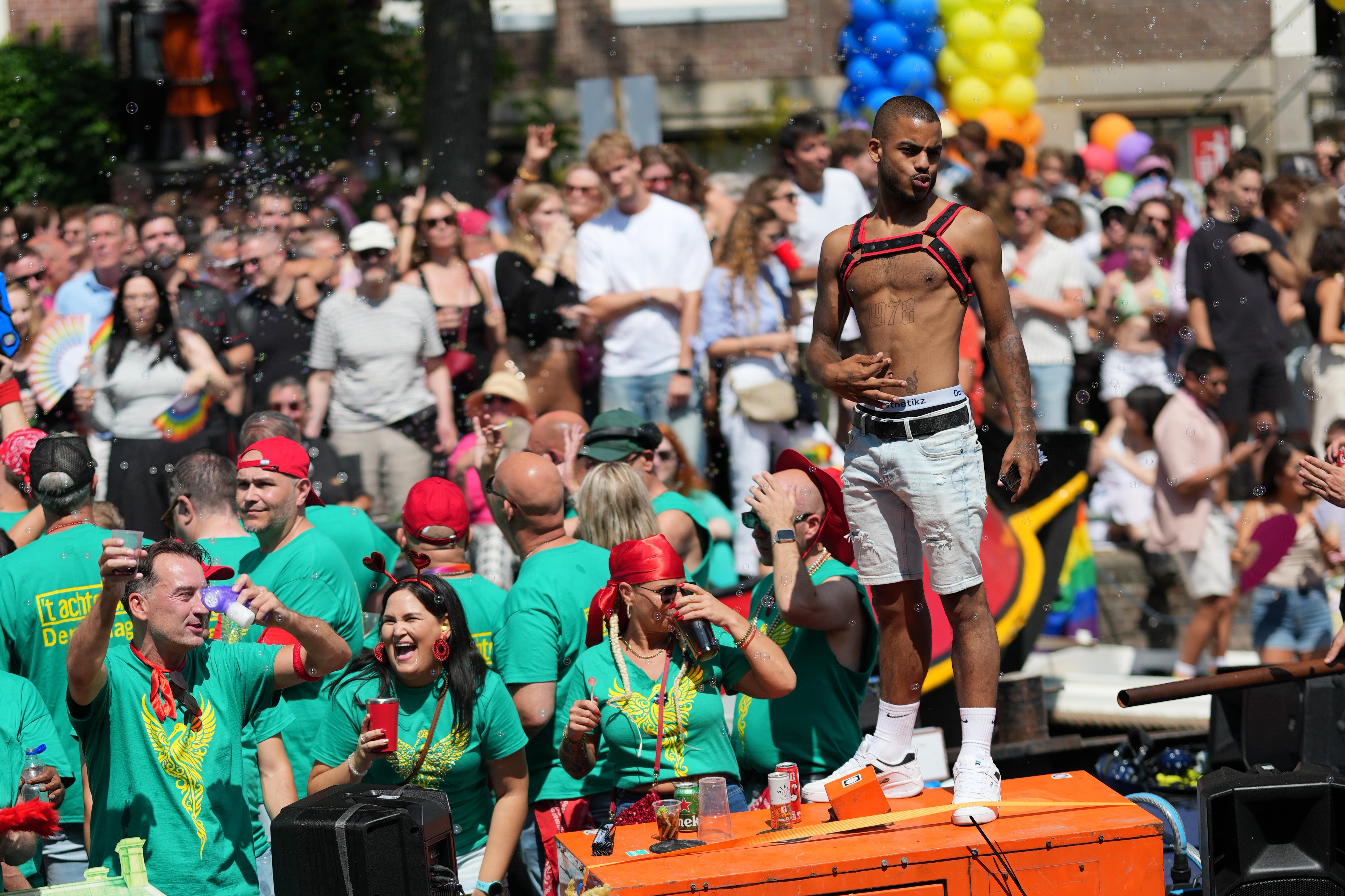 a striking guy posing as bubbles from bubble guns fly around him, at Canal pride in Amsterdam