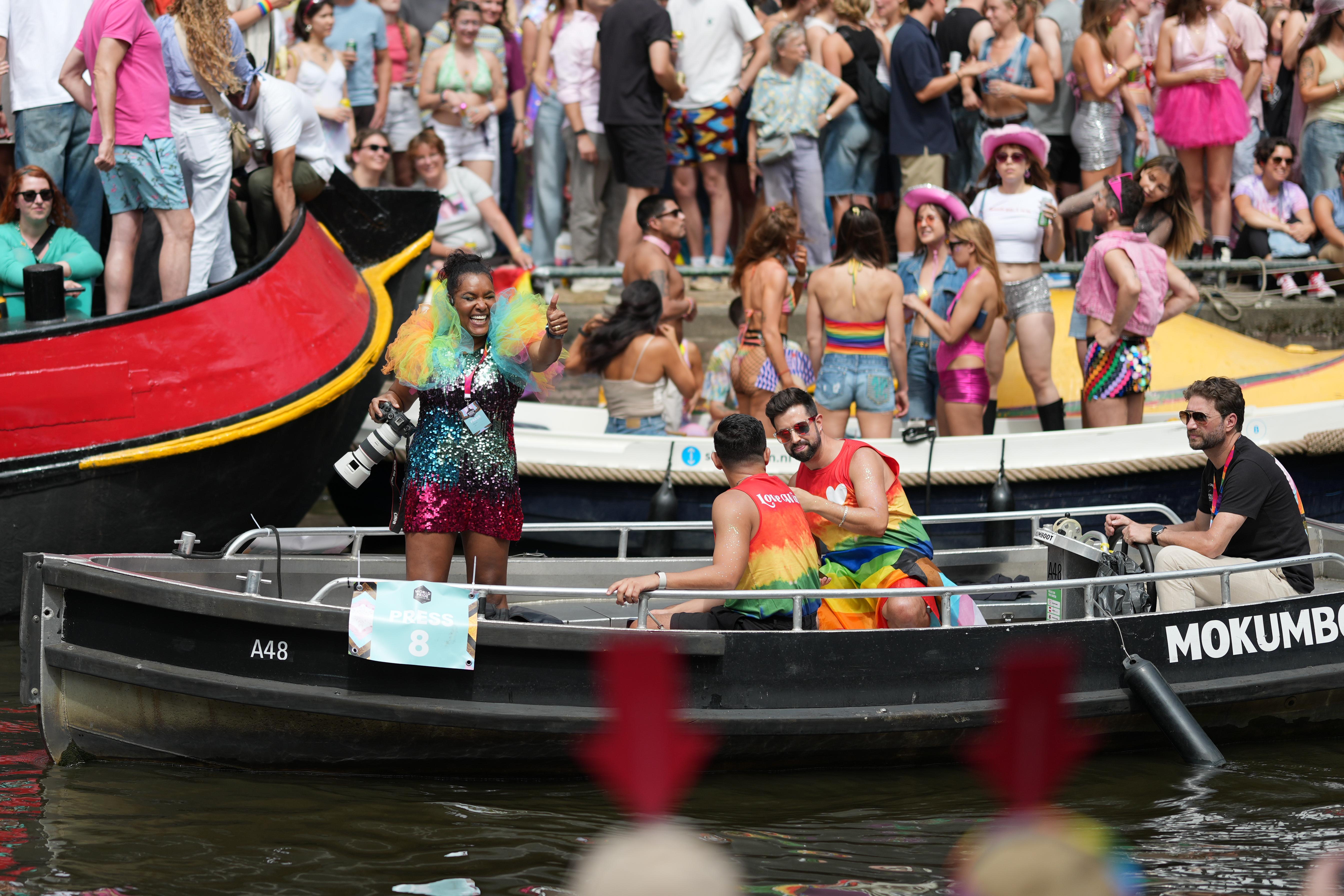 an event press photographer gives a thumbs up to the crowd while holding her Cannon camera at Canal Pride in Amsterdam